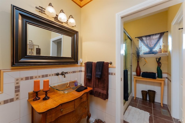 bathroom with a stall shower, tile patterned flooring, tile walls, and a wainscoted wall