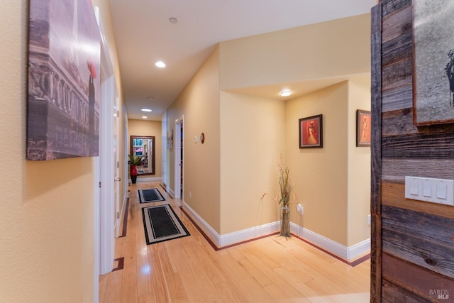 hall with baseboards, light wood-style floors, and recessed lighting