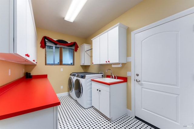 clothes washing area featuring washing machine and dryer, a sink, cabinet space, light floors, and baseboards