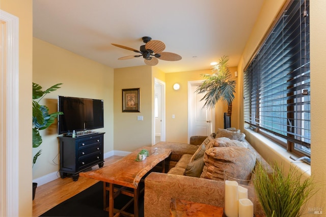 living area featuring baseboards, wood finished floors, and a ceiling fan