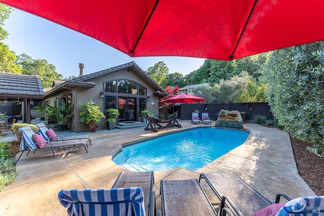 view of pool featuring a fenced backyard, a patio, a fenced in pool, and french doors