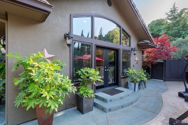view of exterior entry featuring stucco siding, french doors, and a patio