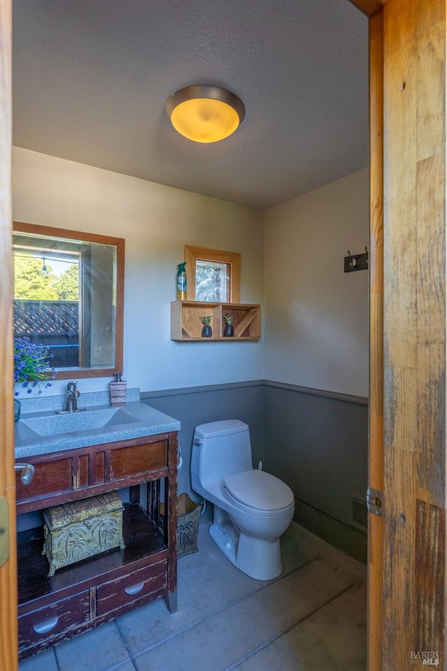 bathroom with vanity, toilet, and visible vents