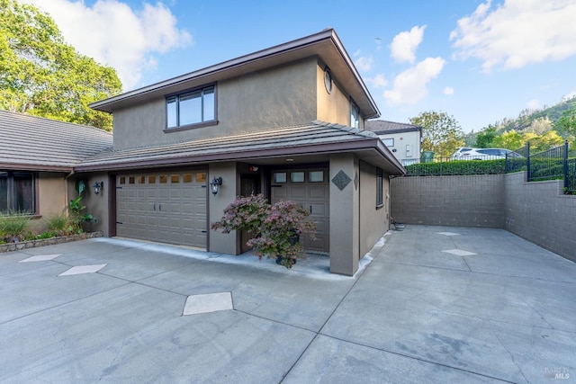 view of front of house featuring fence, an attached garage, stucco siding, and driveway