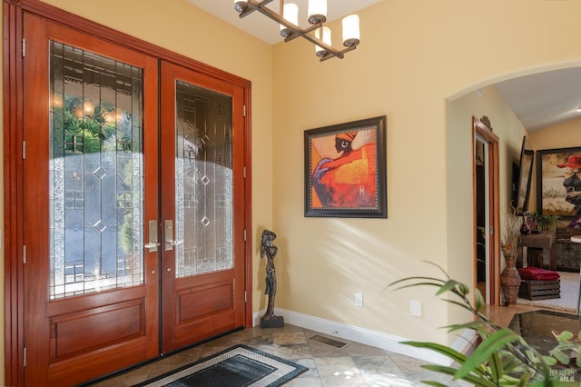 entryway with an inviting chandelier, french doors, visible vents, baseboards, and arched walkways