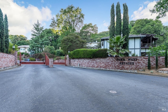 view of street with a gate, curbs, and a gated entry
