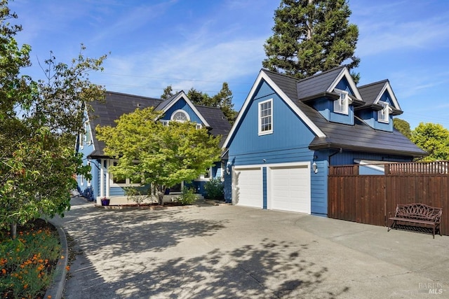 view of front of home featuring concrete driveway, fence, and a garage