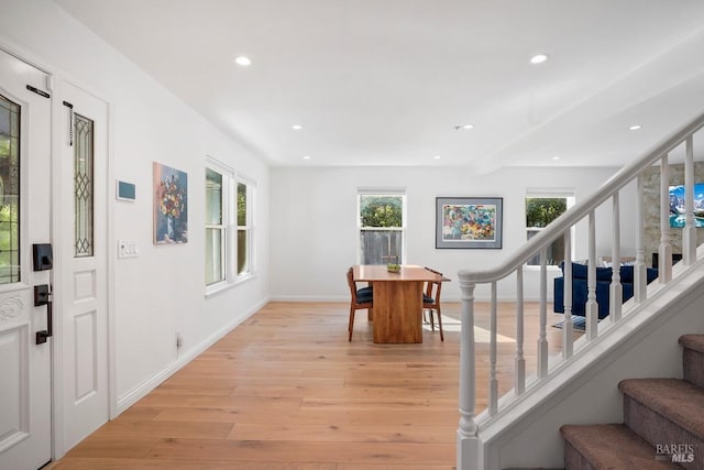 foyer entrance with a wealth of natural light, light wood-style floors, stairway, and recessed lighting