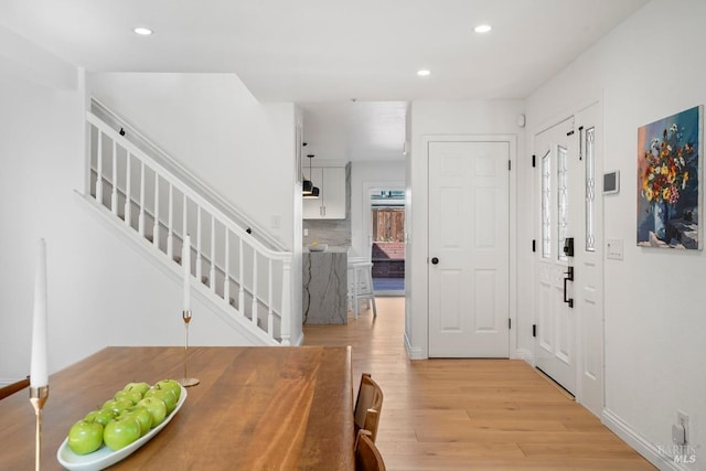 foyer featuring baseboards, stairs, light wood finished floors, and recessed lighting