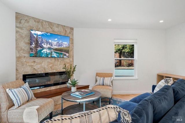 living area featuring baseboards, a fireplace, recessed lighting, and wood finished floors