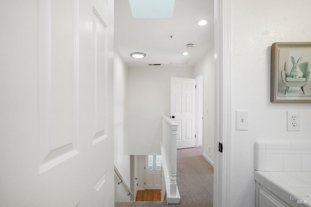 corridor featuring an upstairs landing, a skylight, visible vents, baseboards, and recessed lighting