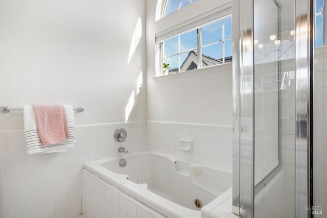 bathroom with a stall shower, tile walls, and a garden tub