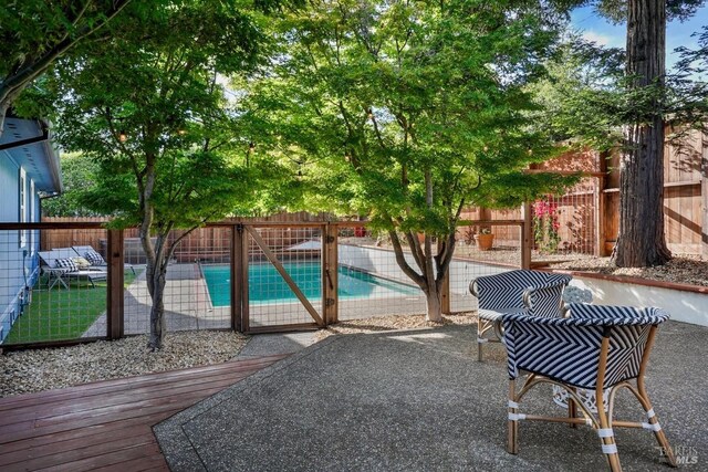 view of patio / terrace with a wooden deck, a fenced in pool, and a fenced backyard