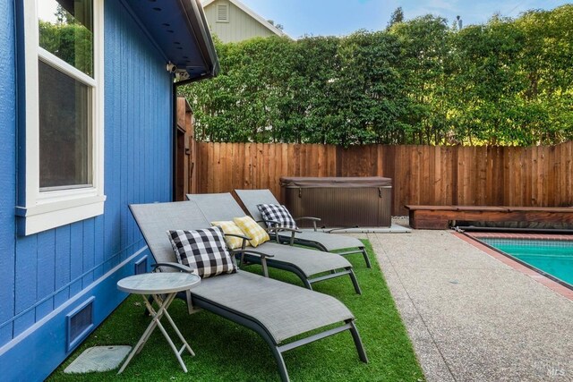 view of patio with a hot tub, visible vents, and fence private yard