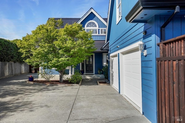 view of front of property featuring concrete driveway, a garage, and fence