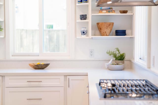 kitchen view of open shelves, light countertops, white cabinetry, and stainless steel gas stovetop