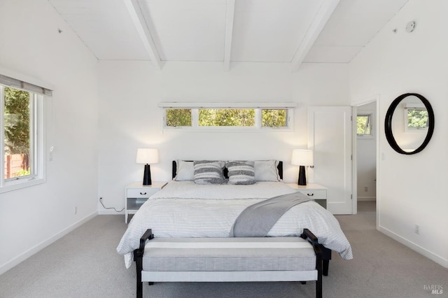 bedroom with light carpet, beamed ceiling, multiple windows, and baseboards