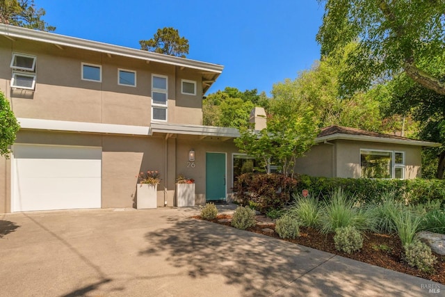 front facade featuring stucco siding, driveway, and an attached garage