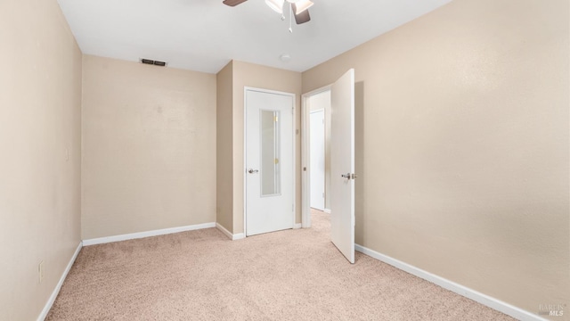 carpeted spare room featuring a ceiling fan and baseboards