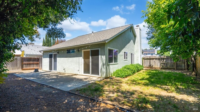 back of property featuring stucco siding, a patio, a fenced backyard, and a chimney