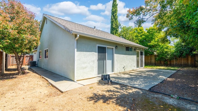 rear view of house featuring stucco siding, central air condition unit, a fenced backyard, and a patio