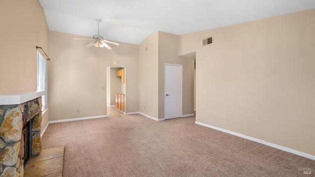 unfurnished living room with a ceiling fan, light colored carpet, high vaulted ceiling, a stone fireplace, and baseboards