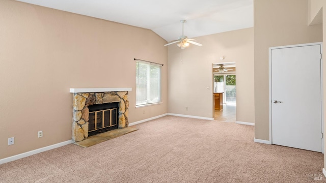 unfurnished living room with a ceiling fan, a stone fireplace, carpet, baseboards, and vaulted ceiling