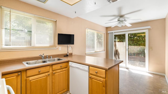 kitchen featuring white dishwasher, a peninsula, a sink, a ceiling fan, and light countertops
