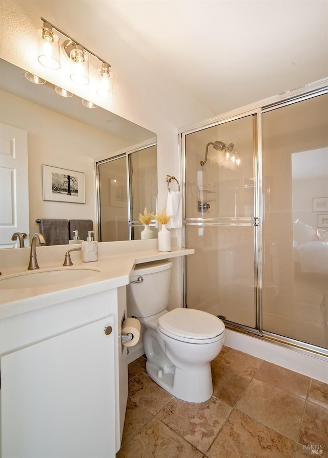 full bath featuring toilet, a stall shower, and vanity