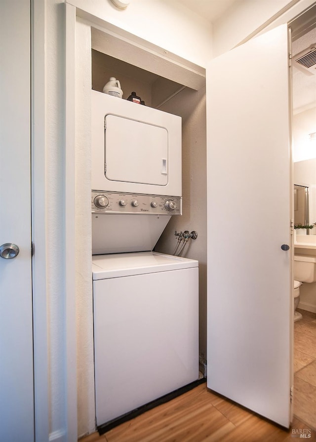 clothes washing area featuring stacked washer / dryer and light wood finished floors