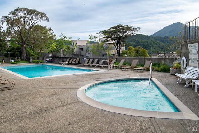 community pool featuring a mountain view, a patio area, and fence