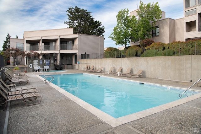 community pool with a patio area and fence