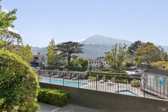 community pool featuring fence, a mountain view, and a patio