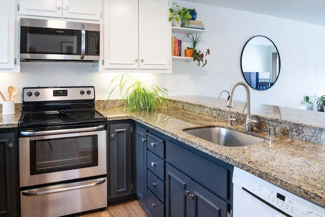 kitchen with appliances with stainless steel finishes, a sink, white cabinets, blue cabinets, and open shelves