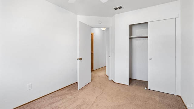unfurnished bedroom with light carpet, a closet, and ceiling fan
