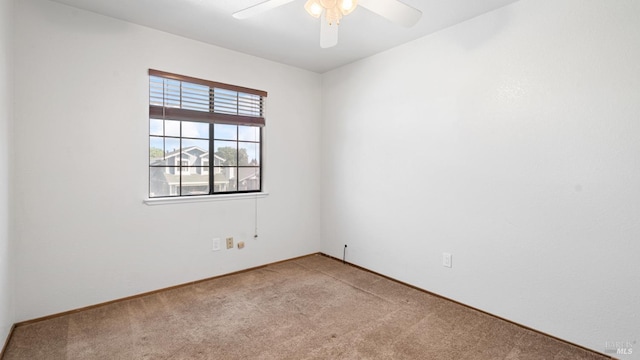 carpeted spare room with a ceiling fan and baseboards