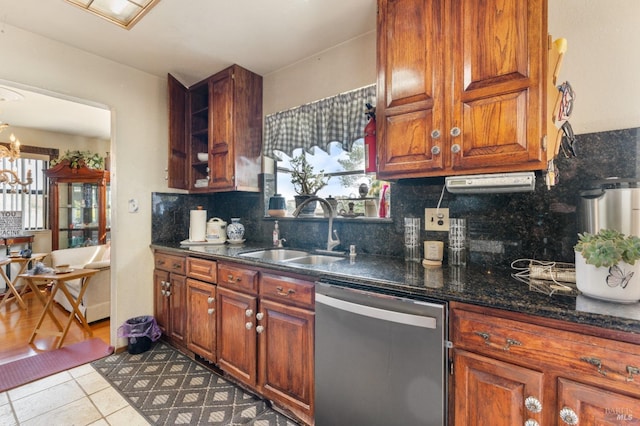 kitchen with stainless steel dishwasher, a sink, backsplash, a chandelier, and tile patterned flooring