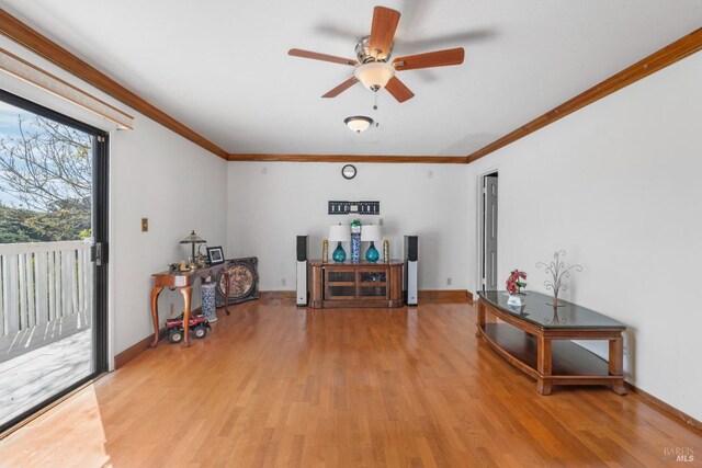 living area with light wood-style flooring, a ceiling fan, ornamental molding, and baseboards