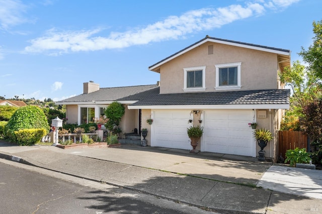 traditional-style home with stucco siding, driveway, a garage, fence, and a chimney