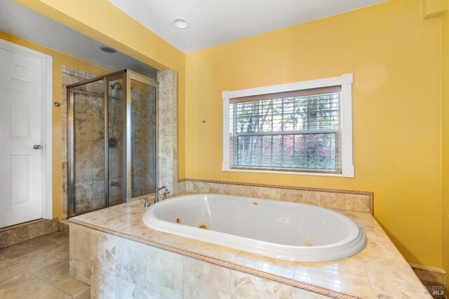 bathroom featuring a stall shower, a tub with jets, and tile patterned flooring