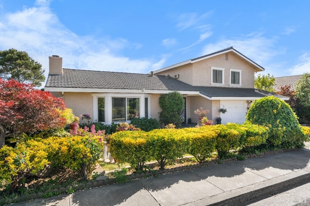 traditional home featuring stucco siding, a chimney, a tile roof, and a garage