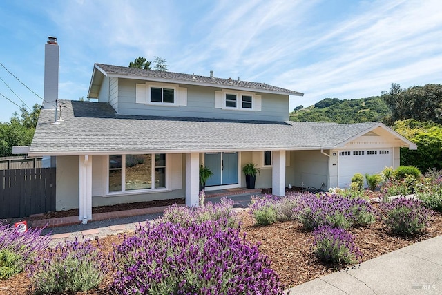 view of front of home with roof with shingles, fence, covered porch, and a garage