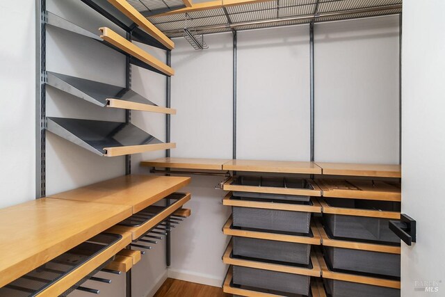 walk in closet with wood finished floors