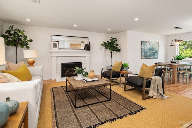 living room with a fireplace, recessed lighting, and light wood-style flooring
