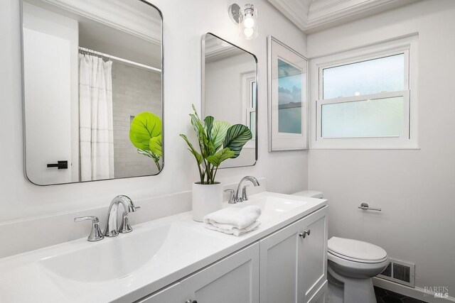 bathroom with toilet, double vanity, and ornamental molding