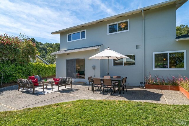 rear view of house featuring stucco siding, a patio, and a forest view