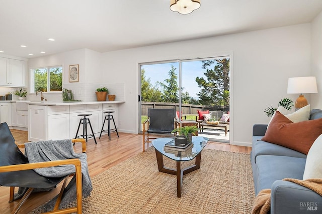 living room with light wood-style floors, recessed lighting, and baseboards