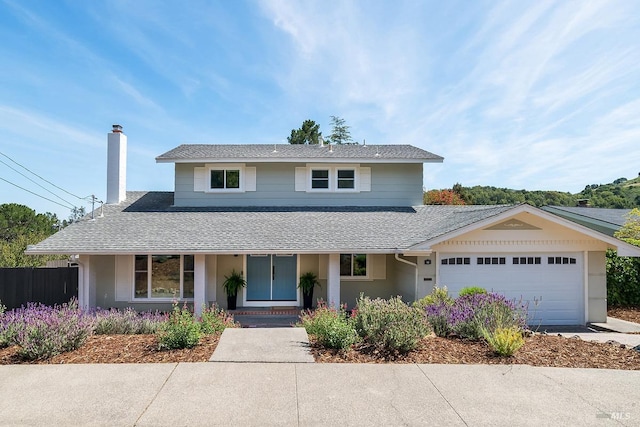 traditional-style house with a chimney, a shingled roof, an attached garage, and fence