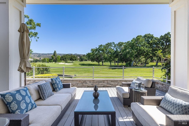 wooden deck with an outdoor living space, a yard, view of wooded area, and view of golf course