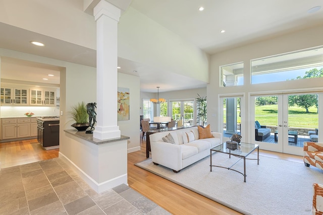 living room featuring ornate columns, recessed lighting, a towering ceiling, and french doors